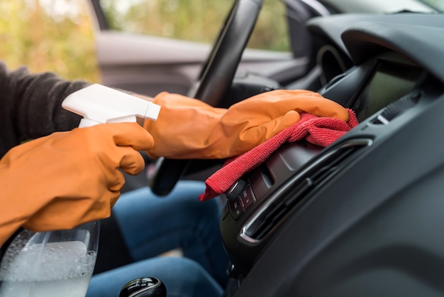 Hand in protective gloves cleaning car interior from coronavirus covid-19 using microfiber clothes. safety