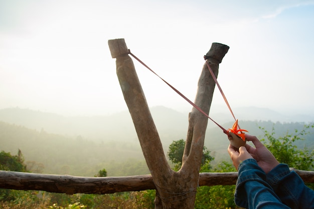 Hand pulling sling shot preparing to shot the tree seed into the forest