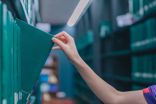 Hand pulling a Thesis book off the shelf in Library