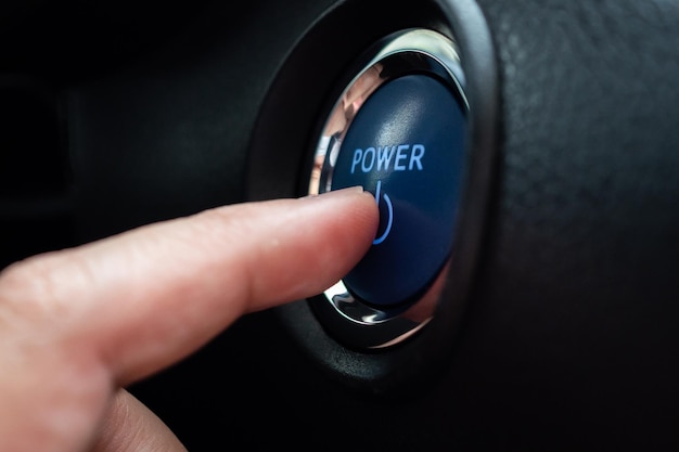 Photo hand push on car engine power start button close up