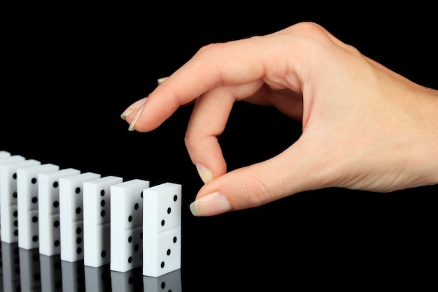 Hand pushing dominoes isolated on black