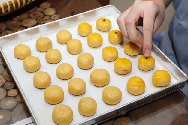 A hand put a clove to each Nastar or Pineapple Tart on aluminum tray before baking