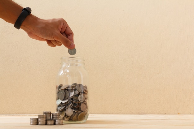 Hand put coin in to glass bottle.finance, economy concept. saving money concept.