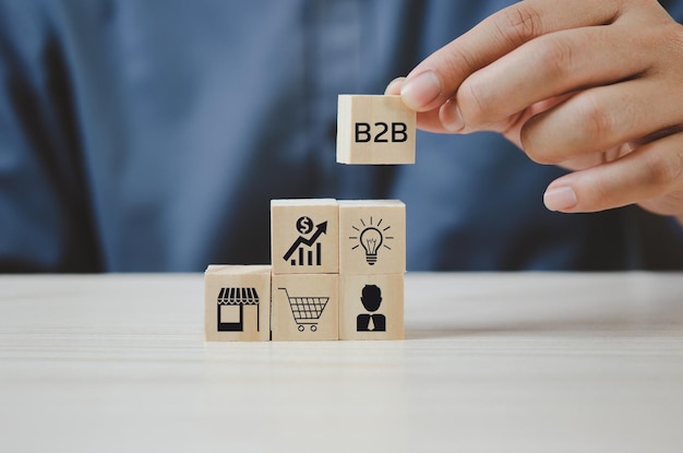 Hand put wooden cubes with B2B Business to Business icons and symbols on table and copy spaceBusiness concepts