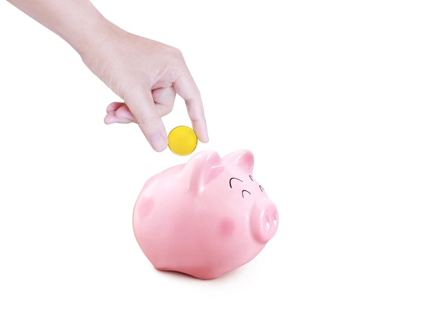 Hand puts gold coins into a piggy bank on a white background