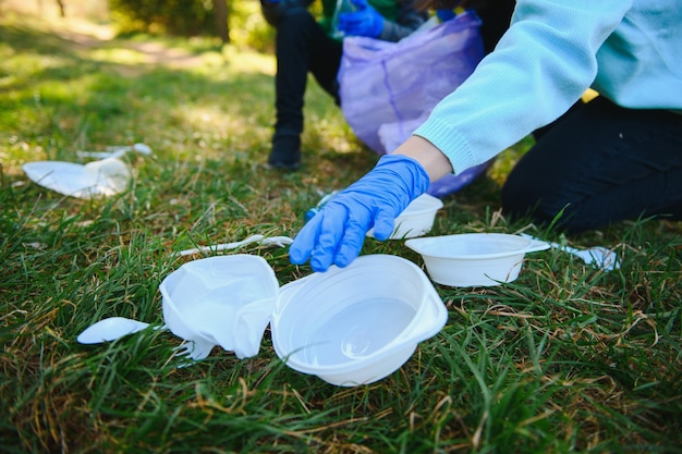 Hand puts plastic debris in the garbage bag in the park