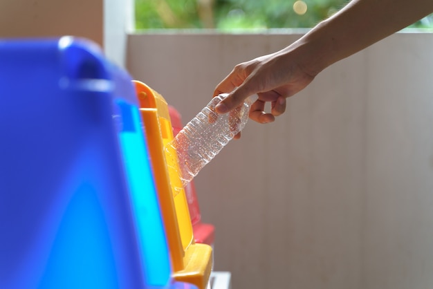 Hand putting bottle to recycle bin