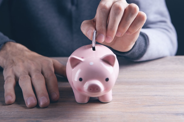 Hand putting coin into piggy bank