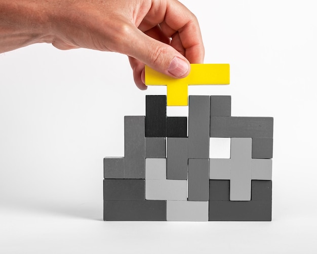 Photo hand putting outstanding yellow element in tetris puzzle formation concept creative unique idea logical game for problem solving skills development