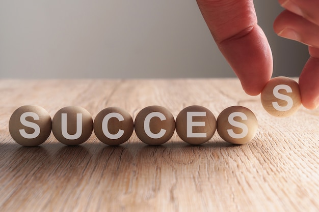 Hand putting on success word written in wooden ball