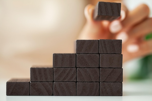 Hand putting wood cube on top of wood block stacking as step stair.