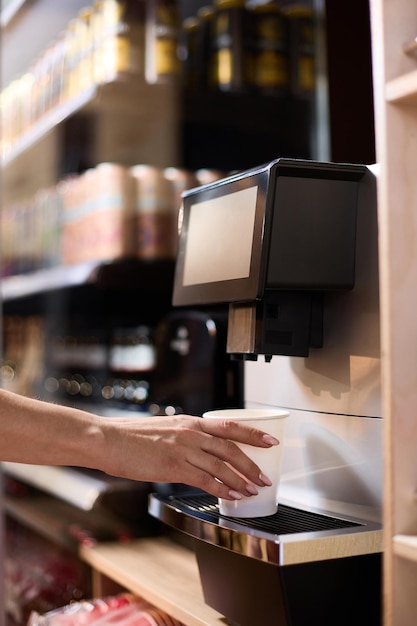 The hand reaches for the cup of coffee that is on the coffee machine