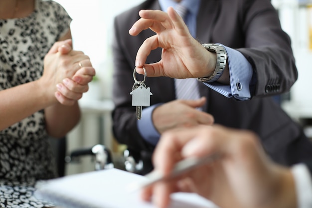 Hand of realtor hold house key aganist office