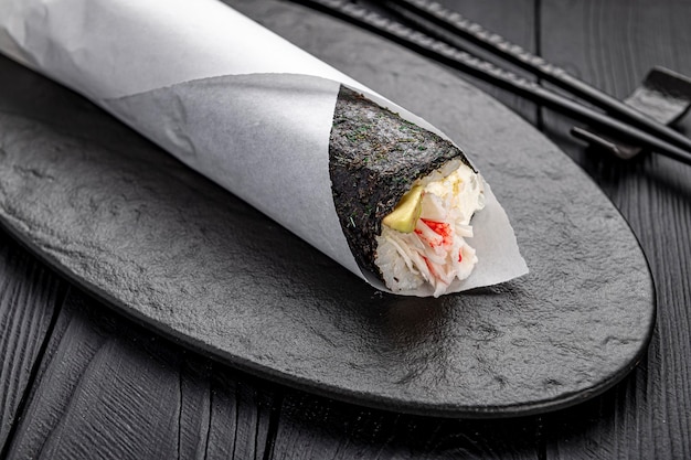 Hand roll with crab avocado and cream cheese on a dark background