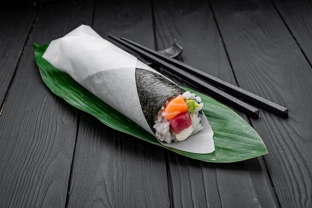 Hand roll with salmon and tuna on a dark background