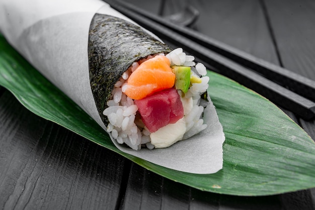 Hand roll with salmon and tuna on a dark background