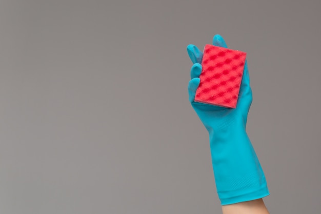 Hand in rubber glove holds color wash sponge on neutral background