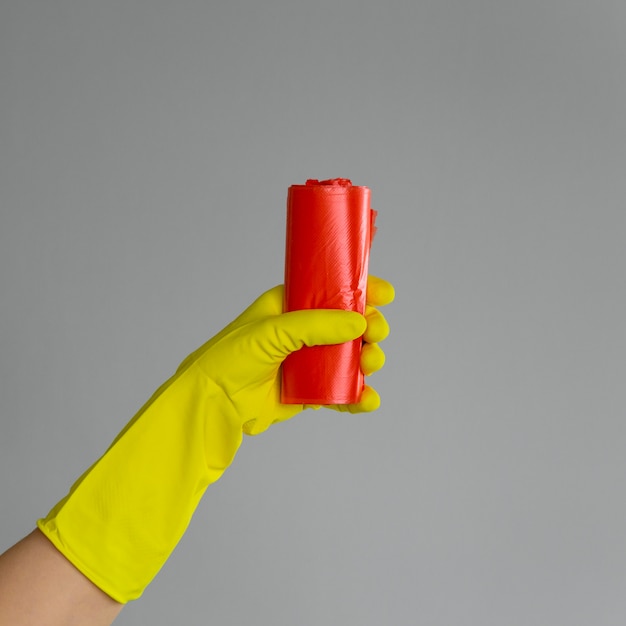 Hand in rubber glove holds colored garbage bag