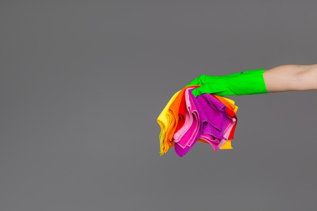 A hand in a rubber glove holds a set of coloured microfibre cloths on neutral. 