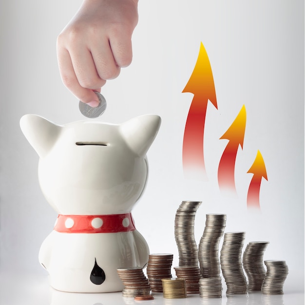 A hand saving coin in piggy bank with graphic on white background