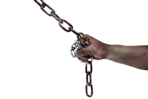 The hand of a scary zombie with blood and wounds tied on the iron chain is isolated over a white background