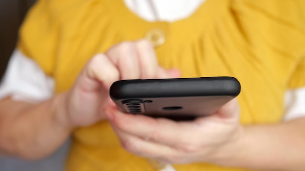 Hand of senior woman typing message to friend on smartphone