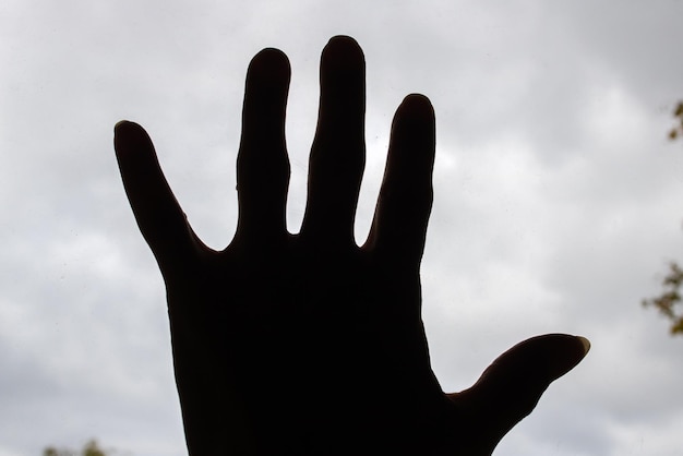 Hand shadow on glass against sky background