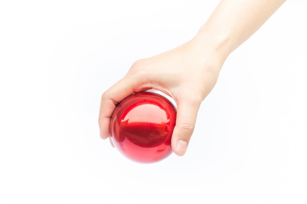 Hand on shiny red ball on white background