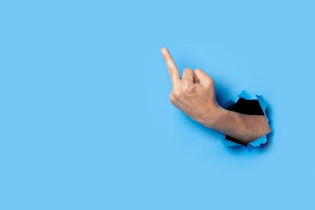 Hand shows the gesture of the middle finger on blue