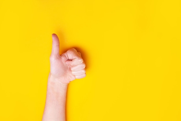 Hand shows thumbs up on a yellow background. Class approval concept