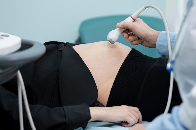 Hand slides transducer over abdomen checking signs of foetus