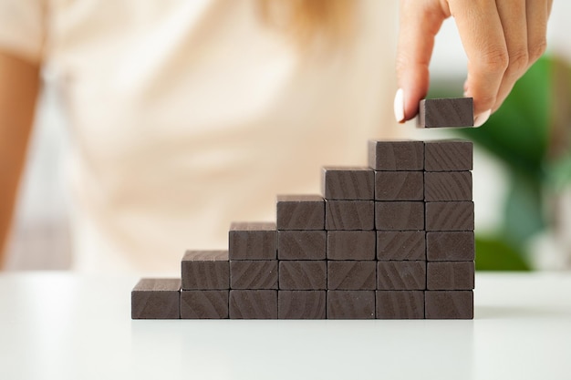 Hand stacking wooden black blocks for in shape of staircase