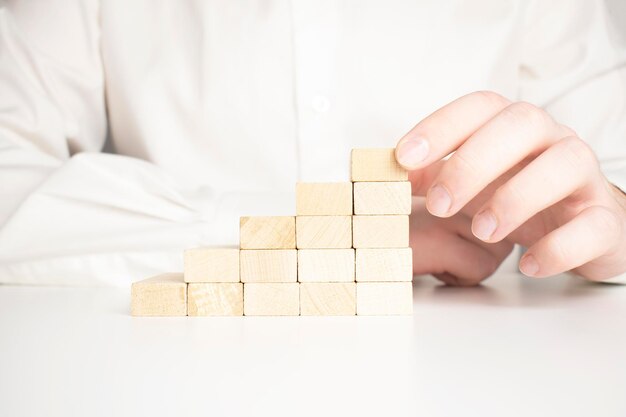 Hand stacking wooden blocks for in shape of staircase Business development strategy concept Building success foundation