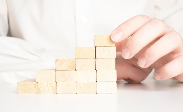 Hand stacking wooden blocks for in shape of staircase Business development strategy concept Building success foundation