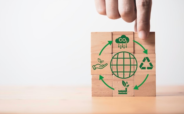 Hand stacking world and CO2 reducing Recycle Green factory icon for decrease CO2 carbon footprint and carbon credit to limit global warming from climate change Bio Circular Green Economy concept