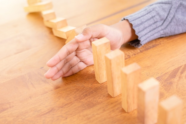 Hand stop wooden block, creating a domino risk effect 