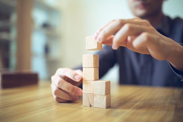 Hand strategically placing wooden blocks in a stairstep design Success and growth