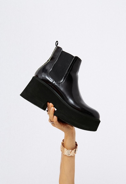 Hand in the studio holds platform boots Trendy shoes Minimalist fashion style concept