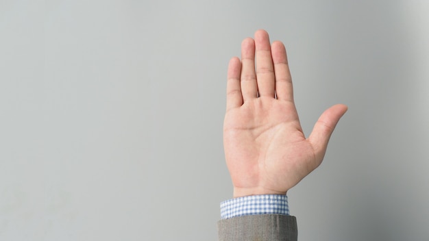 Hand suit and empty palm in grey suit color on grey background. Businessman topic.close up photo and studio shooting.