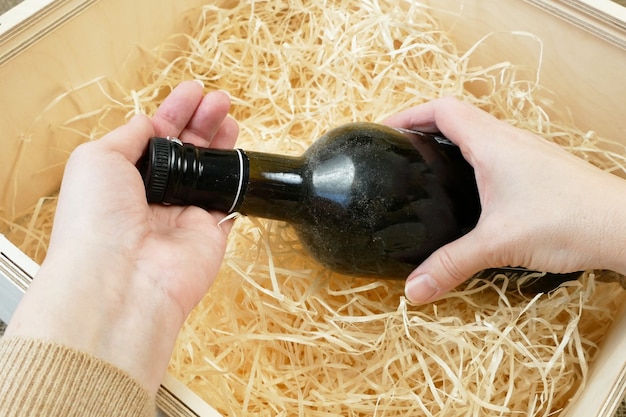 Hand take out the bottle of wine from the wooden box