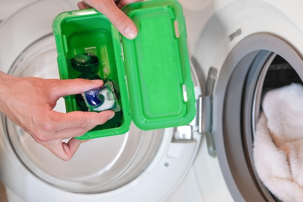 Hand takes out the washing capsule and puts it in the washing machine before washing