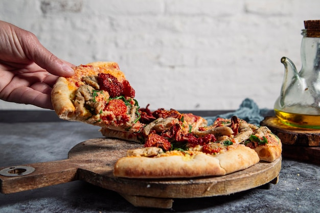 The hand takes a piece of homemade vegan pizza