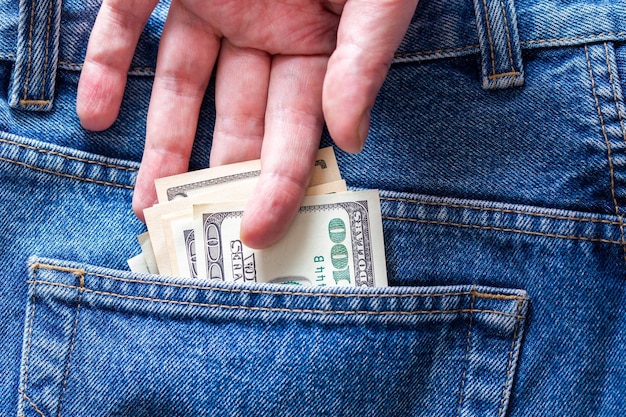 A hand taking hundred dollar banknote from rear jeans pocket