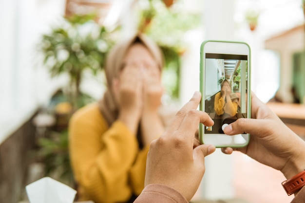 Hand taking a picture of a veiled girl close face with hand using a smartphone