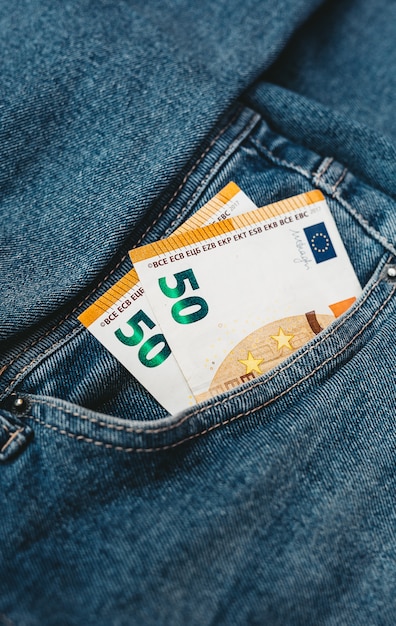 The hand that puts euro banknotes in a pocket of jeans