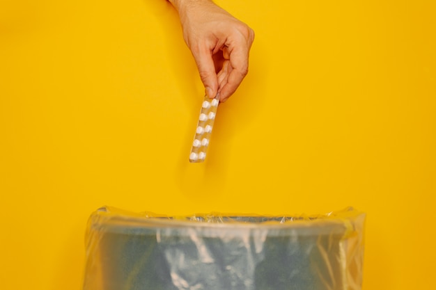 Hand throwing pills away in trash