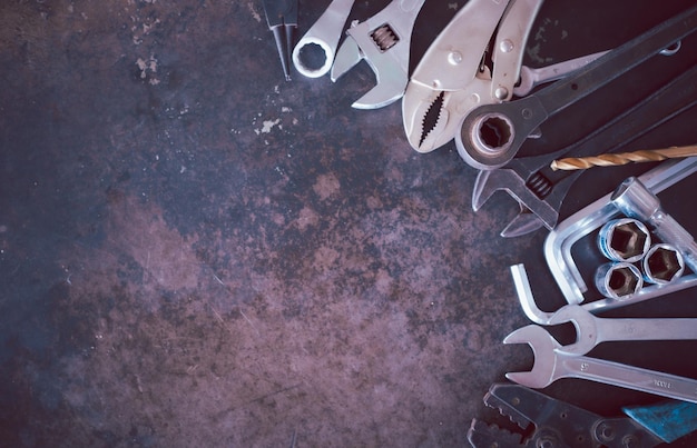 Hand tools consisting of wrenches pliers socket wrenches laid out on old steel plate background