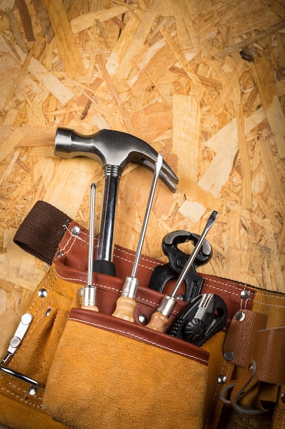 Hand Tools In Tool Belt On plate Of Pressed Wood Waste Close-up