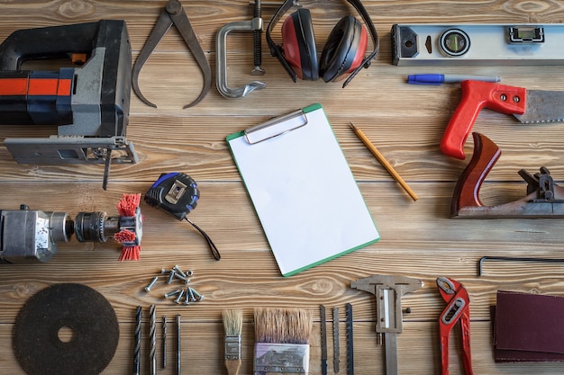 Hand tools on wooden boards. In the center there is a sheet of paper with a pencil.