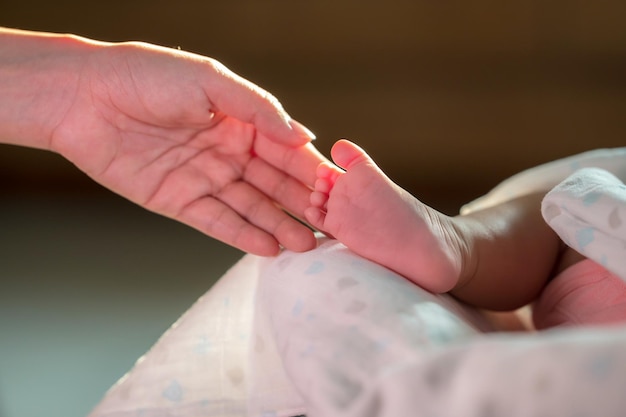 Hand touching newborn baby foot with love